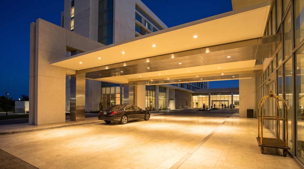 A hotel porte-cochere at night with a vehicle under the illuminated arrival canopy